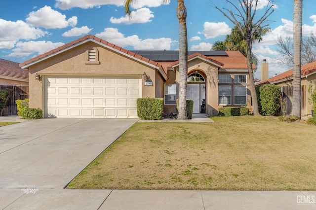 mediterranean / spanish-style home with an attached garage, a tiled roof, roof mounted solar panels, stucco siding, and a front lawn