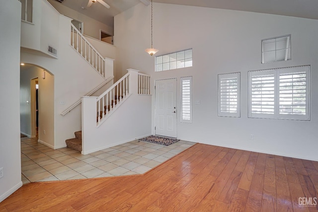 entryway featuring light hardwood / wood-style floors, a towering ceiling, and beam ceiling