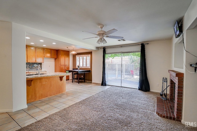 kitchen featuring ceiling fan, sink, backsplash, a kitchen bar, and light tile patterned floors