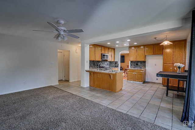 kitchen featuring stainless steel appliances, backsplash, kitchen peninsula, a breakfast bar, and light tile patterned floors