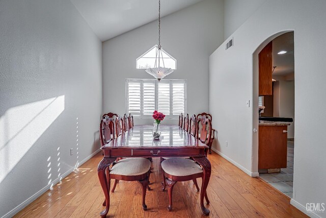 dining area featuring high vaulted ceiling and light hardwood / wood-style floors