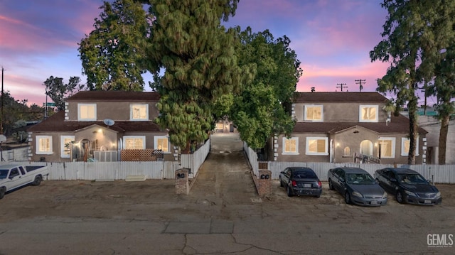 view of front of house with a fenced front yard, uncovered parking, and stucco siding