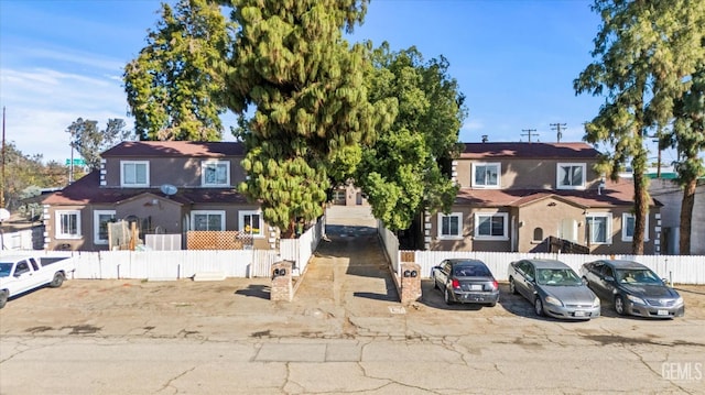 view of front of home with a fenced front yard and uncovered parking