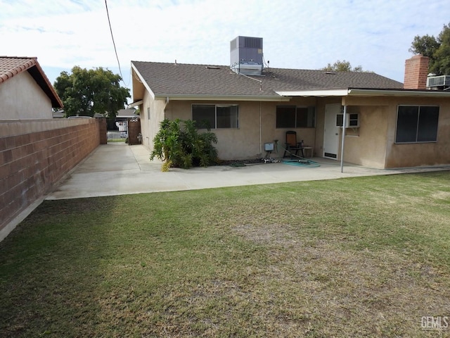 back of property featuring central air condition unit, a patio area, a yard, and a wall mounted AC