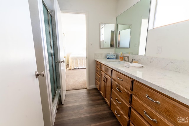 bathroom with hardwood / wood-style floors, vanity, and a shower with shower door