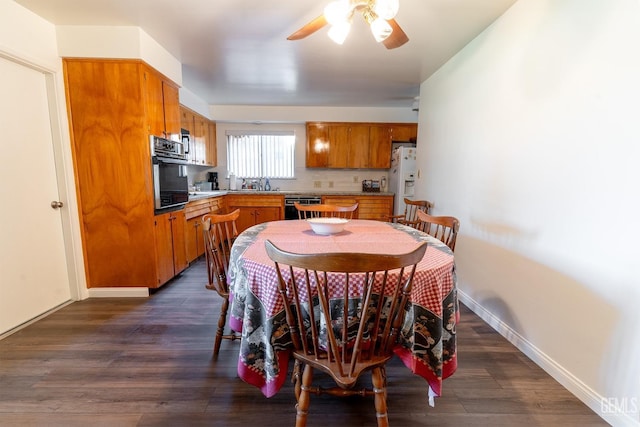 dining area with ceiling fan, dark hardwood / wood-style floors, and sink