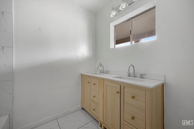 bathroom with double vanity, marble finish floor, baseboards, and a sink