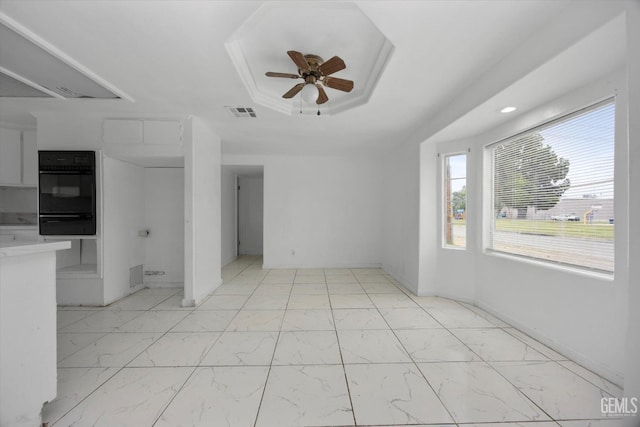 unfurnished living room featuring a ceiling fan, marble finish floor, a raised ceiling, and visible vents