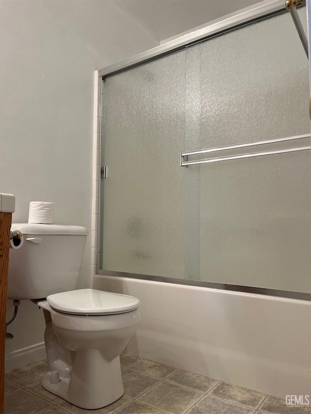 bathroom featuring tile patterned flooring, toilet, and bath / shower combo with glass door