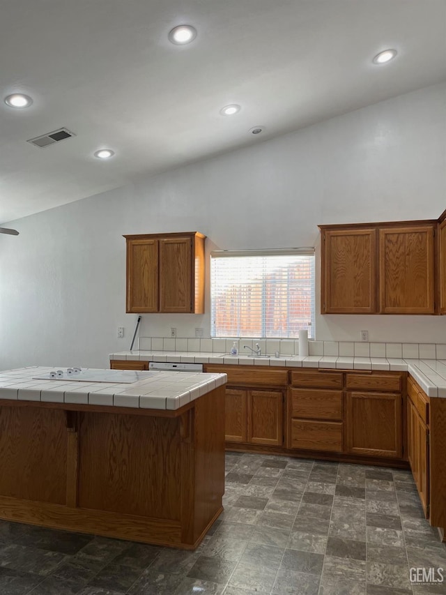 kitchen featuring kitchen peninsula, a kitchen bar, sink, tile countertops, and lofted ceiling