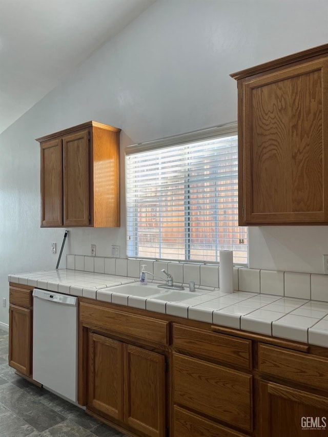 kitchen with white dishwasher, lofted ceiling, sink, and tile countertops