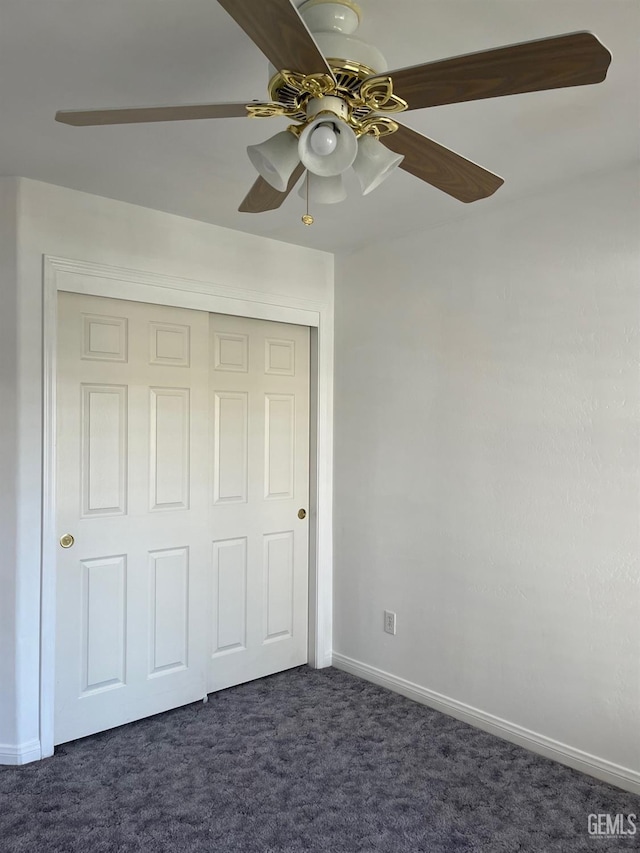 unfurnished bedroom featuring ceiling fan, dark carpet, and a closet