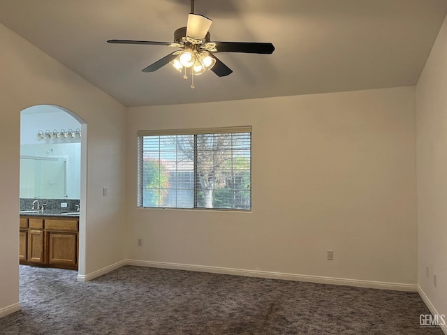 unfurnished room featuring dark colored carpet, vaulted ceiling, ceiling fan, and sink