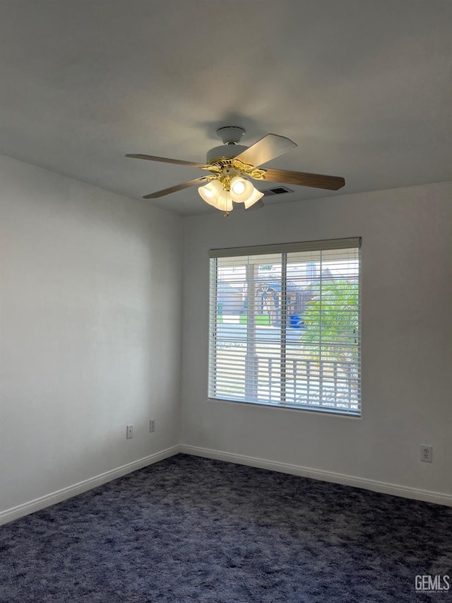 spare room with ceiling fan and dark carpet