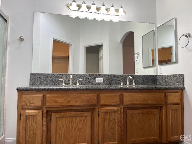 bathroom featuring a shower with door and vanity