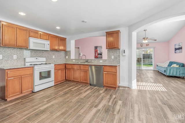 kitchen with white appliances, light wood-type flooring, backsplash, ceiling fan, and sink