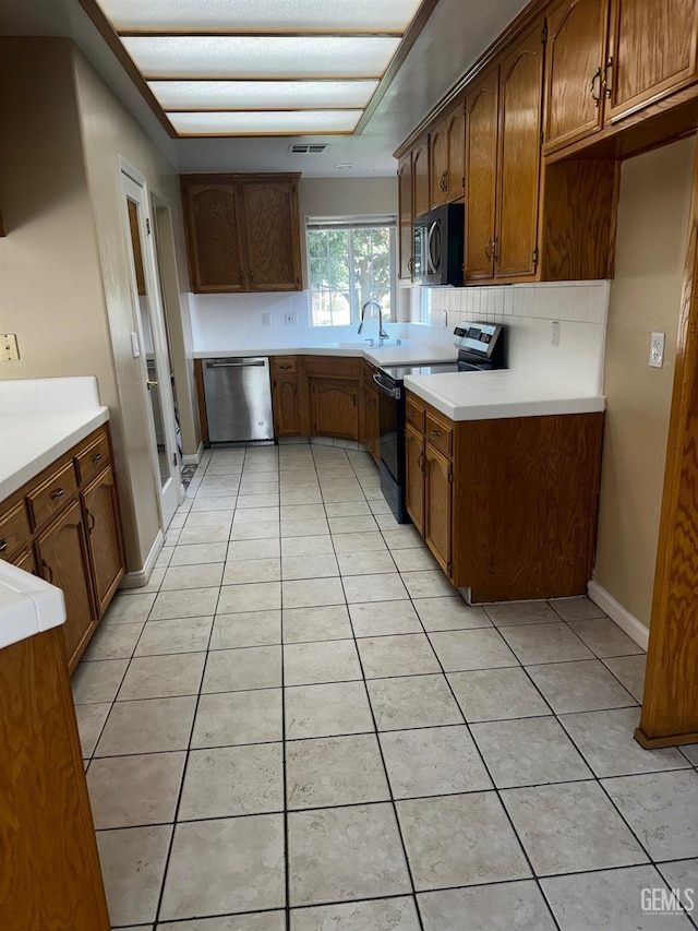 kitchen featuring electric range, dishwasher, light tile patterned flooring, and tasteful backsplash