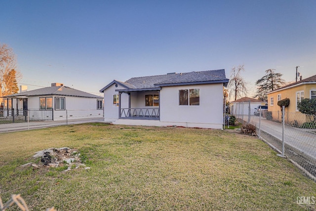 back of property featuring stucco siding, fence, and a yard