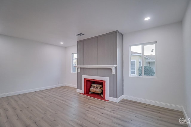 unfurnished living room with recessed lighting, a large fireplace, wood finished floors, visible vents, and baseboards