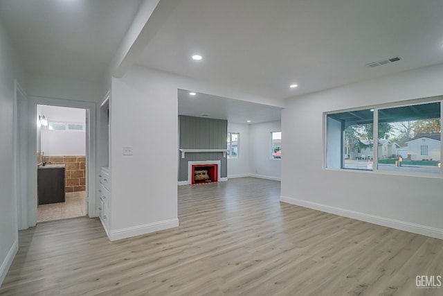 unfurnished living room with light wood-type flooring, a fireplace, and a healthy amount of sunlight