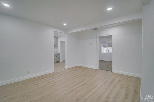 empty room with light wood-style floors, recessed lighting, visible vents, and baseboards