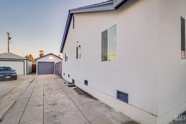 view of side of home featuring a garage, an outbuilding, and stucco siding