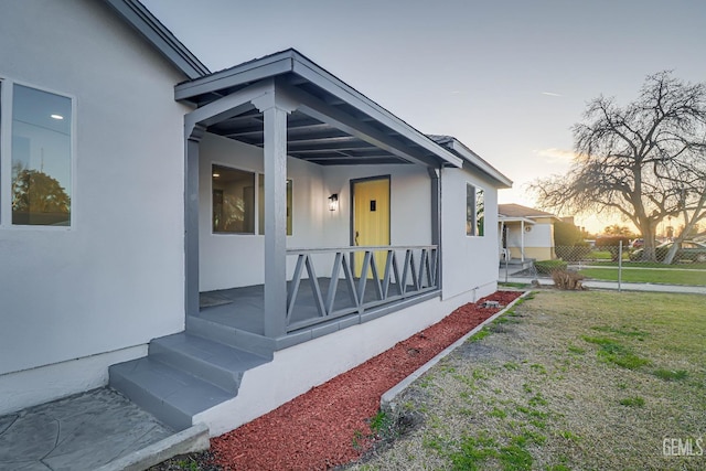 view of side of property featuring a porch, a yard, and stucco siding