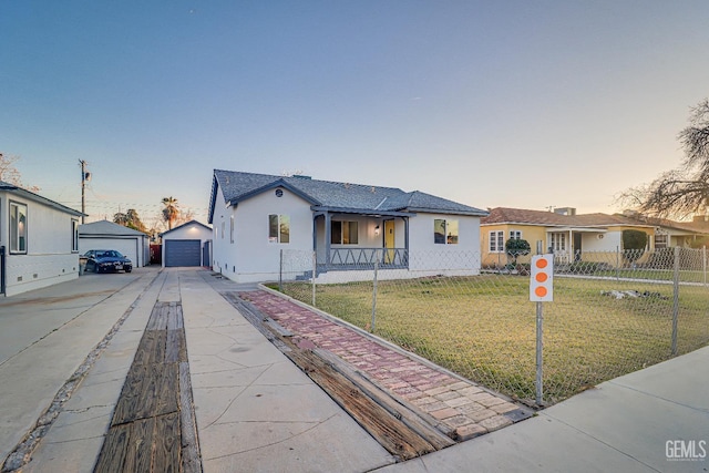 view of front of property featuring a garage, a yard, fence, an outdoor structure, and stucco siding