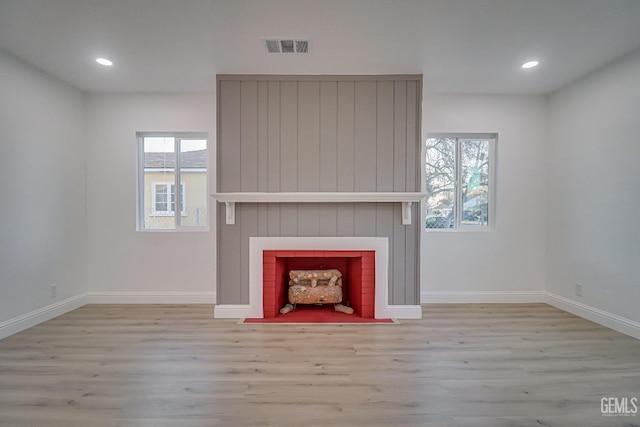 unfurnished living room with recessed lighting, a large fireplace, wood finished floors, visible vents, and baseboards