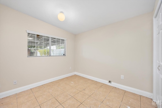 unfurnished room with light tile patterned floors and lofted ceiling