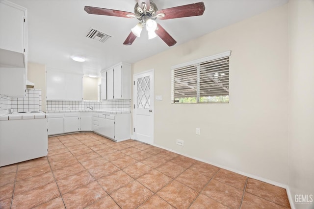 kitchen featuring white cabinets, ceiling fan, light tile patterned flooring, and tasteful backsplash