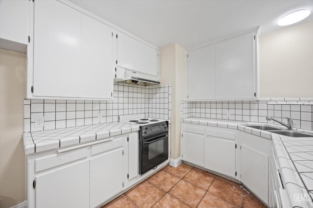 kitchen with tile countertops, electric range, sink, and white cabinets