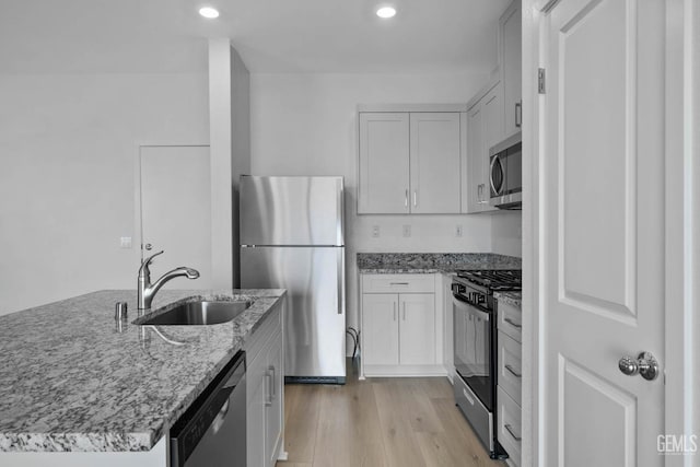 8407 Seth Alexander Way, Bakersfield, CA 93306 - kitchen with stainless steel appliances, a sink, light stone countertops, light wood-style flooring, and recessed lighting