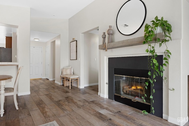 living area with baseboards, wood finished floors, visible vents, and a tile fireplace