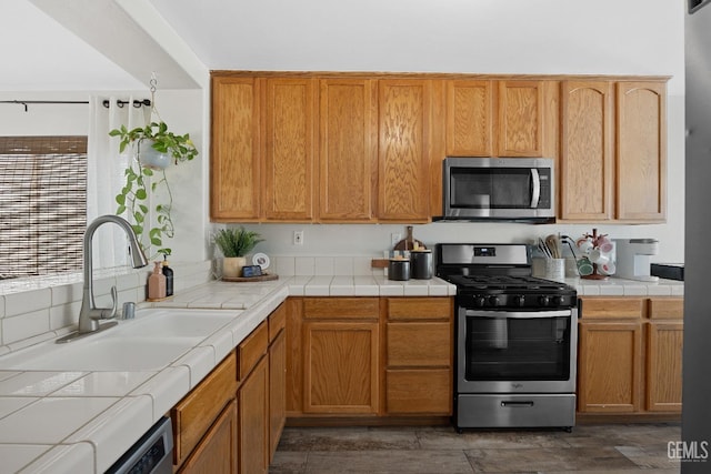 kitchen featuring tile countertops, appliances with stainless steel finishes, and a sink