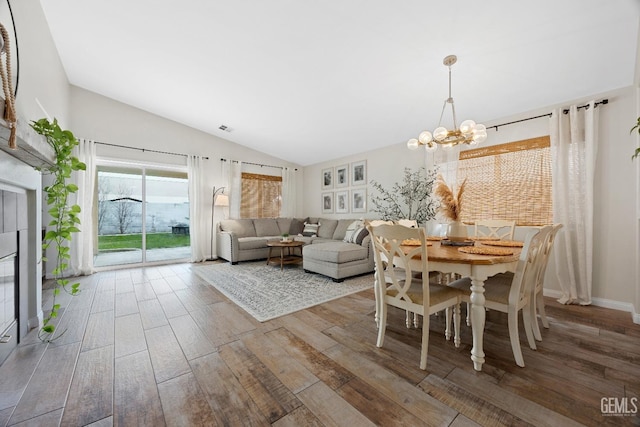 dining space featuring vaulted ceiling, a notable chandelier, wood finished floors, and visible vents