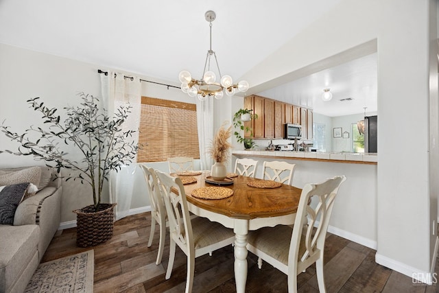 dining room featuring baseboards, dark wood-type flooring, and a chandelier