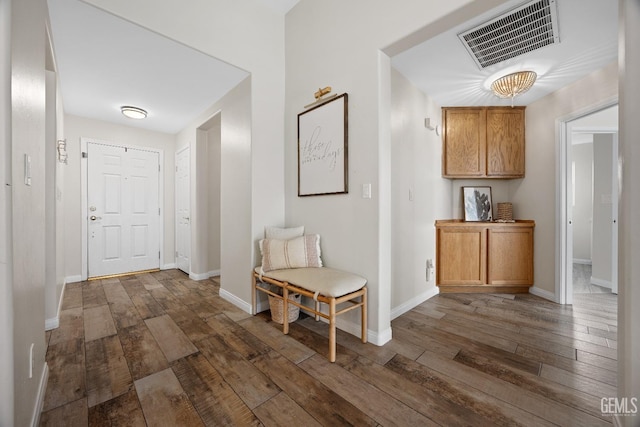 hall featuring visible vents, baseboards, and hardwood / wood-style flooring