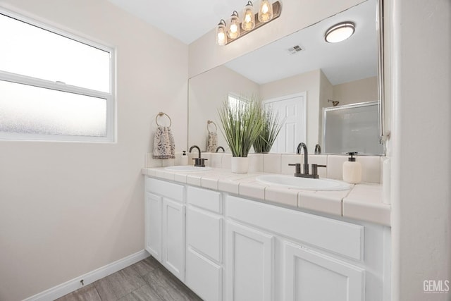 bathroom with a shower stall, baseboards, visible vents, and a sink