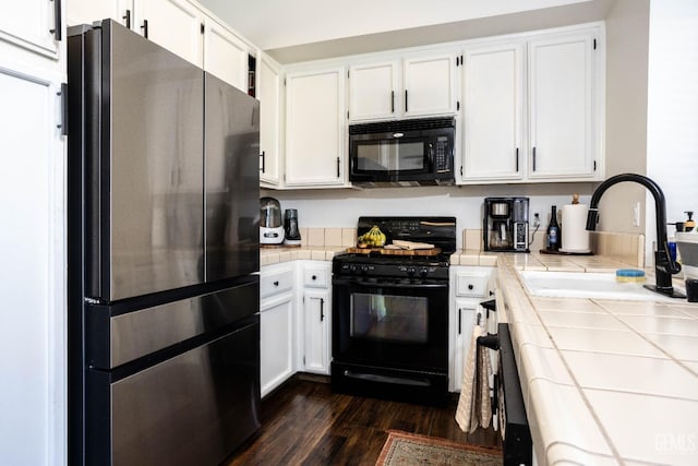 kitchen with black appliances, white cabinetry, tile countertops, and sink