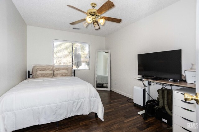 bedroom with a textured ceiling, dark hardwood / wood-style floors, and ceiling fan