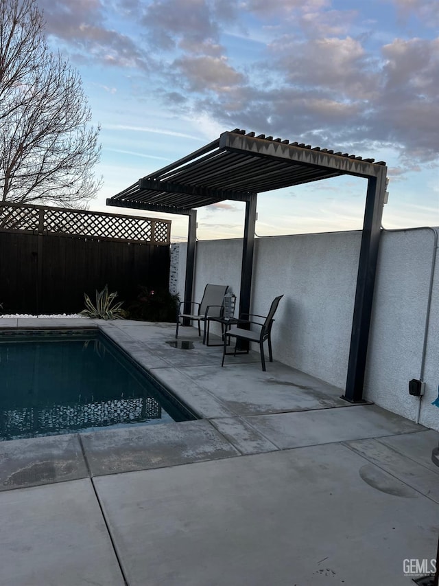 pool at dusk featuring a pergola and a patio