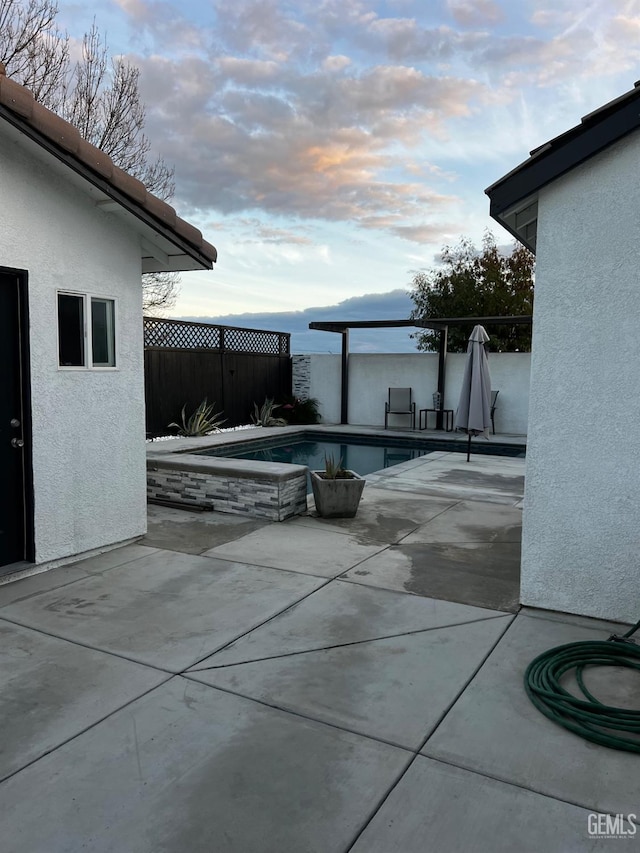 pool at dusk featuring a patio