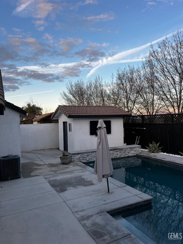 pool at dusk featuring central AC unit and a patio