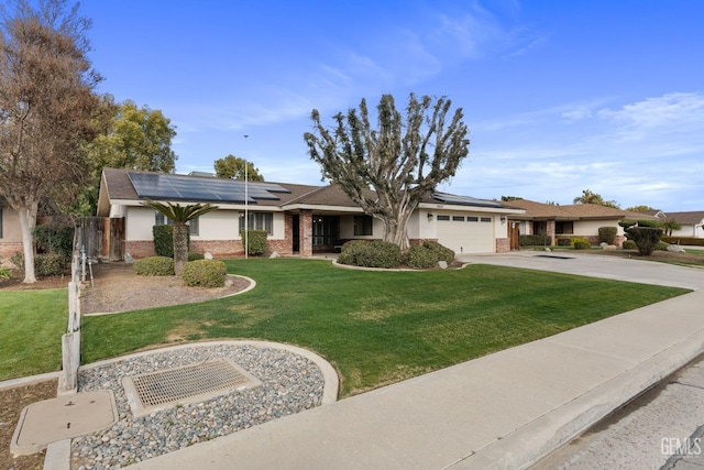 ranch-style house with brick siding, roof mounted solar panels, a garage, driveway, and a front lawn