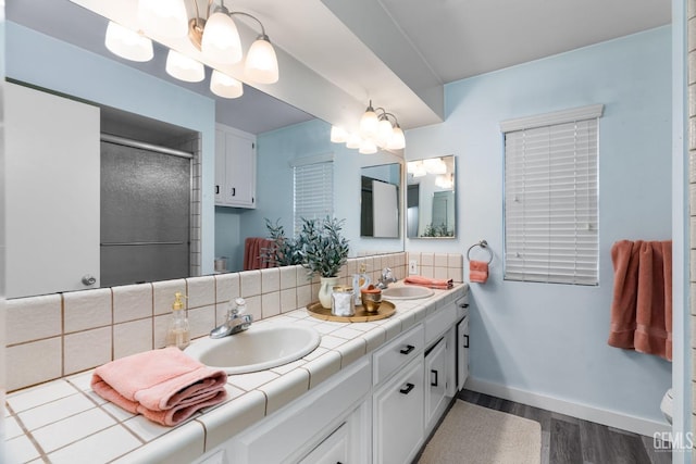 bathroom with tasteful backsplash, a stall shower, a sink, and double vanity