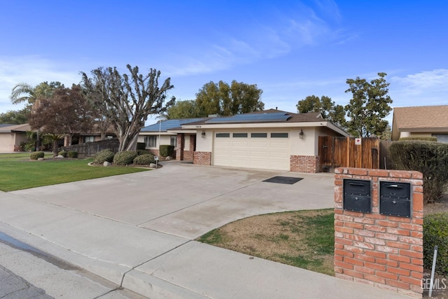 ranch-style home featuring a garage, brick siding, fence, driveway, and roof mounted solar panels