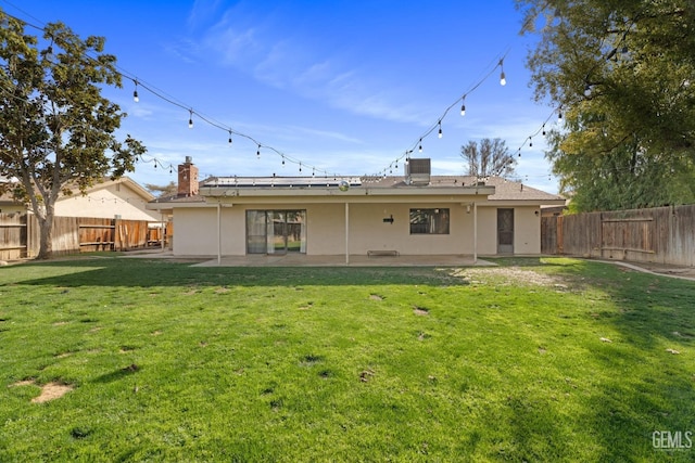 rear view of property featuring a patio area, a fenced backyard, a lawn, and stucco siding