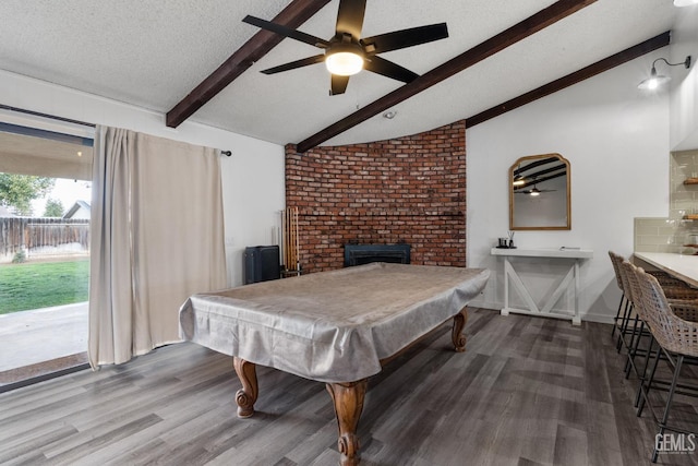 recreation room featuring a brick fireplace, lofted ceiling with beams, a textured ceiling, and wood finished floors