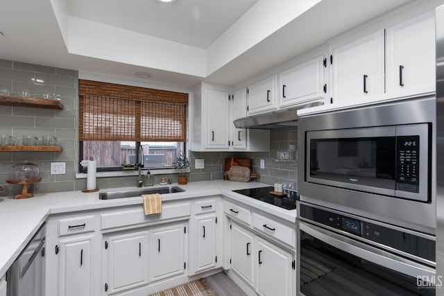 kitchen featuring tasteful backsplash, light countertops, appliances with stainless steel finishes, white cabinetry, and a sink